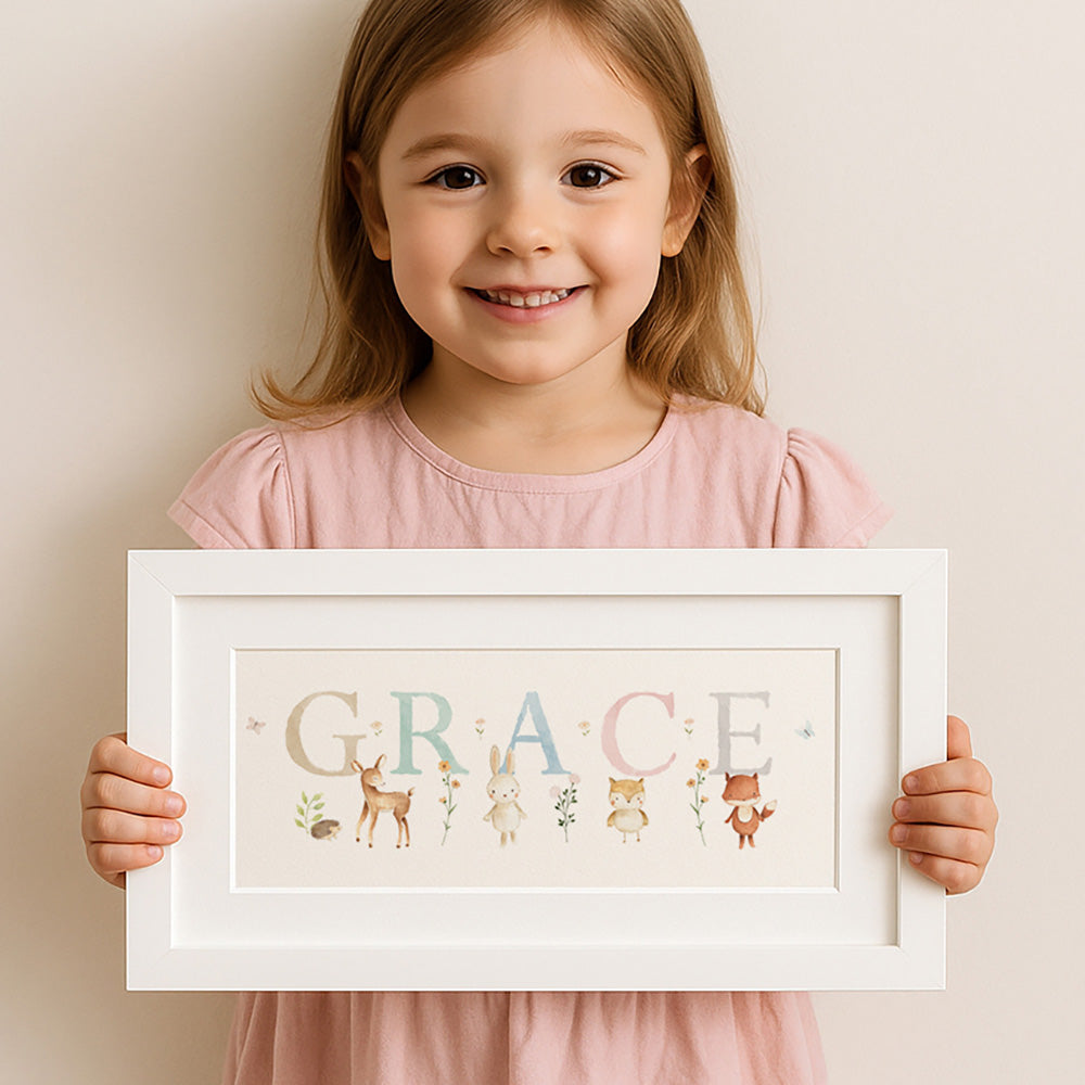 Young girl holding a framed name 'GRACE' with illustrations on a plain background
